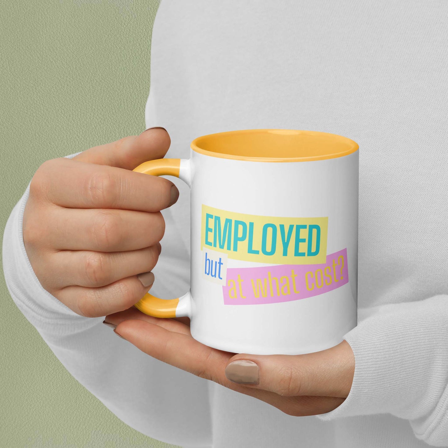 Hand holding a mug with text 'EMPLOYED but at what cost?' on a plain background