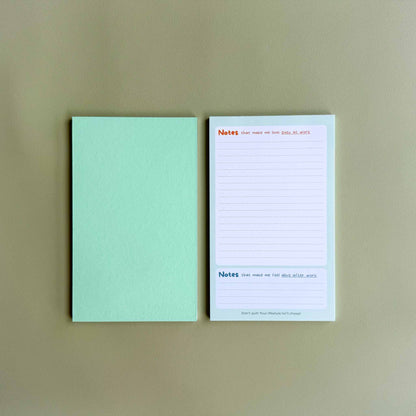 Two 'Busy at work, alive after work' dual-section notepads — one face up showing the dual 'Notes' layout and one face down showing the green back