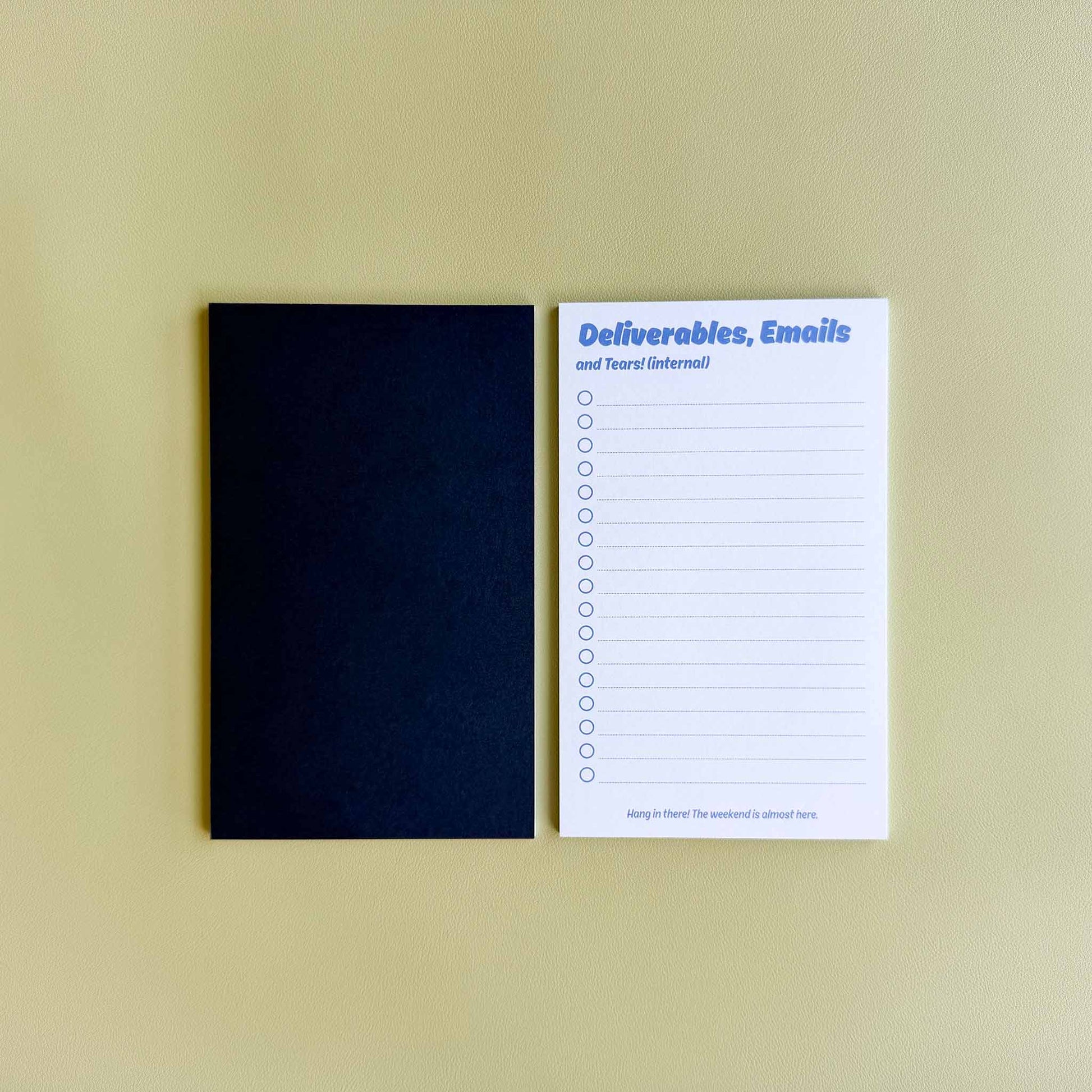 Two 'Deliverables, emails, and tears (internal)' to-do list notepads — one face up showing the checklist layout and one face down showing the dark blue back